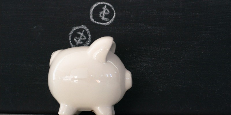 Piggy bank against chalkboard  wall, money drawn on wall 