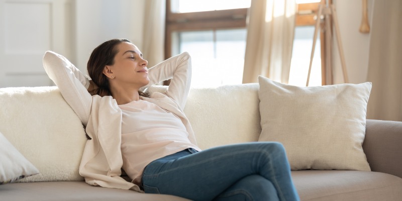 lady relaxing on couch with arms behind head