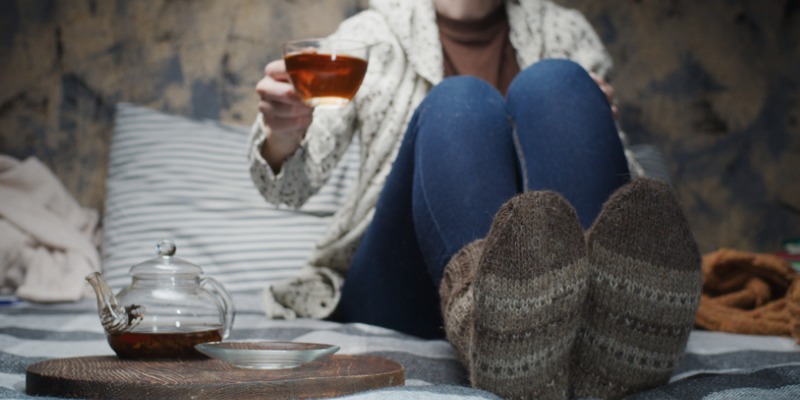 woman sitting on the couch with warm socks on and tea